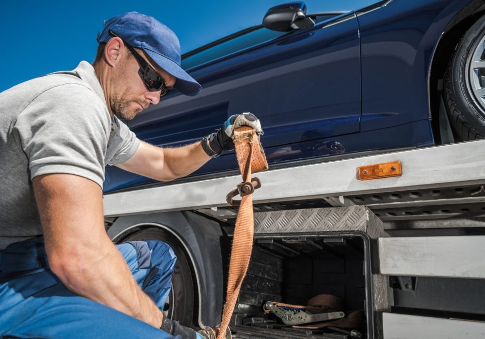 Caucasian Repo Company Worker in His 40s Securing Repossessed Vehicle on His Towing Truck. Automotive Car Loans Concept.